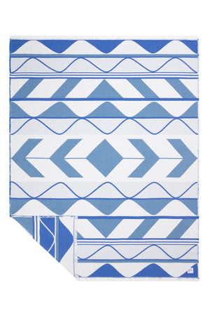 A beautiful blue and white Indigenous blanket. The bottom-left corner is folded over to show the reverse side, which has a white background with blue  designs.