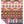 A folded woven blanket with a bold pattern in red, yellow, black, and white, displayed on a clean white background.