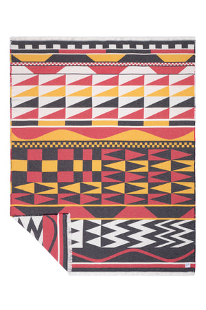 A folded woven blanket with a bold pattern in red, yellow, black, and white, displayed on a clean white background.