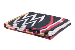 A folded woven blanket featuring a bold pattern in black, white, red, and yellow, set against a plain white background.